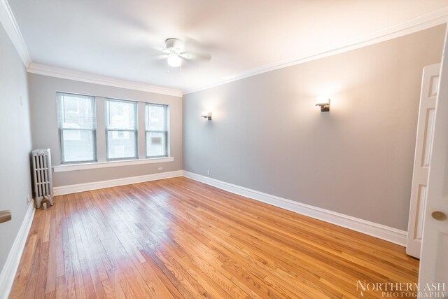 spare room with radiator heating unit, light wood finished floors, a ceiling fan, baseboards, and ornamental molding