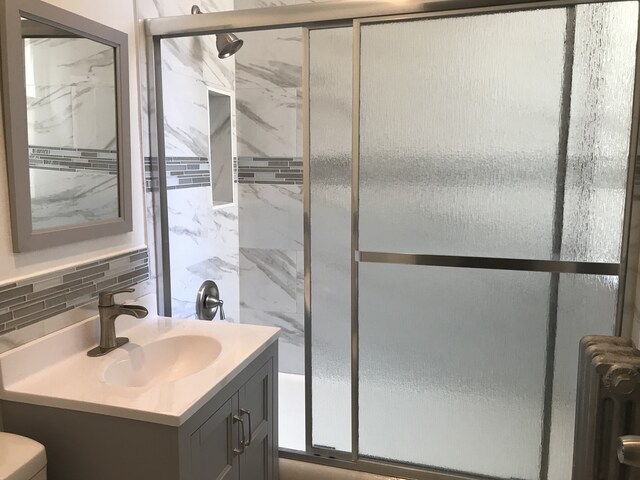 bathroom featuring a stall shower, radiator, vanity, backsplash, and toilet