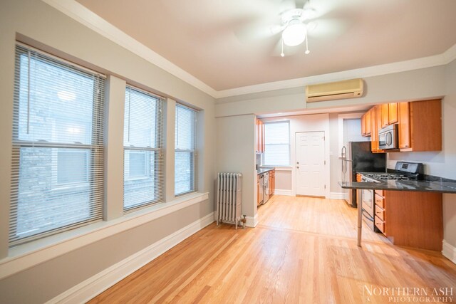 kitchen featuring radiator heating unit, gas stove, an AC wall unit, stainless steel microwave, and dark countertops