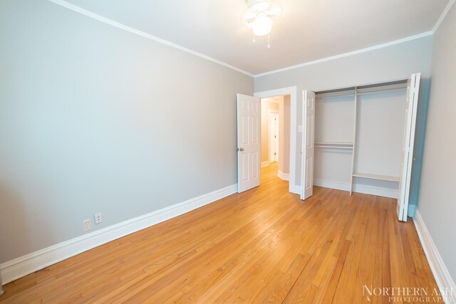 unfurnished bedroom with light wood-style floors, crown molding, baseboards, and a closet