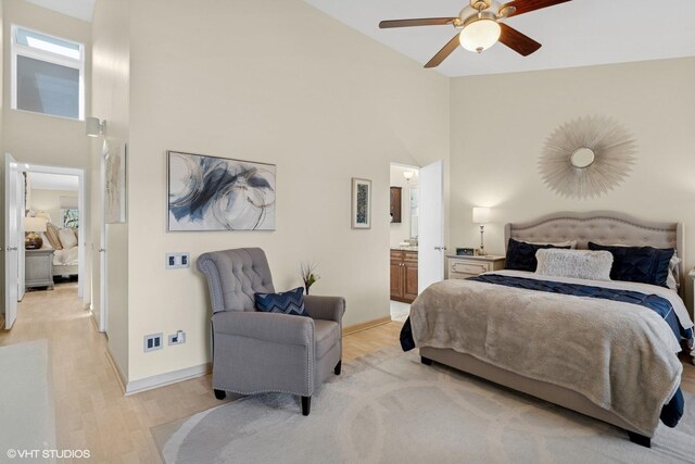 bedroom with high vaulted ceiling, light wood-style floors, baseboards, connected bathroom, and ceiling fan