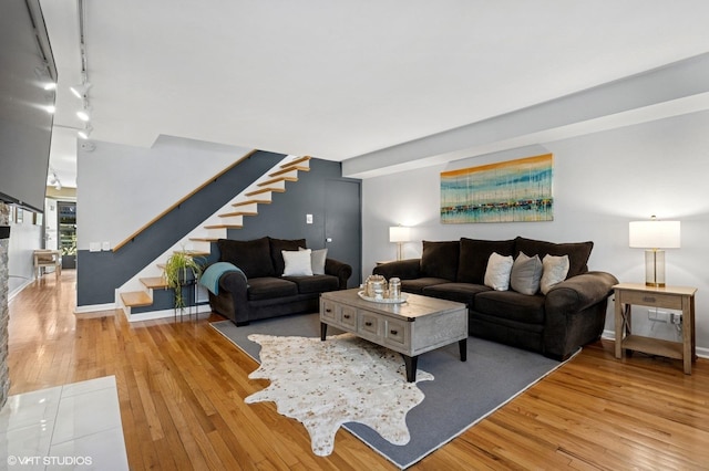 living area with stairs, hardwood / wood-style floors, and track lighting