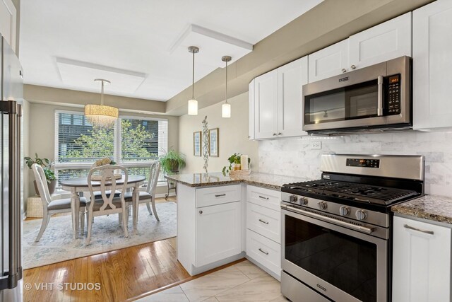 3700 N Lake Shore Dr Unit 312, Chicago, IL 60613 - kitchen with stainless steel appliances, white cabinets, a peninsula, light stone counters, and decorative backsplash
