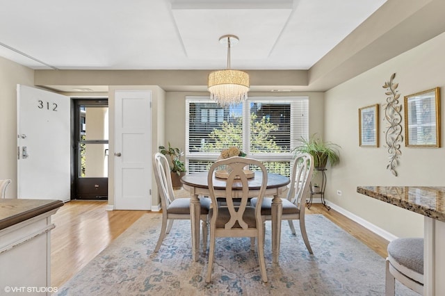 dining space with a chandelier, light wood-style flooring, and baseboards