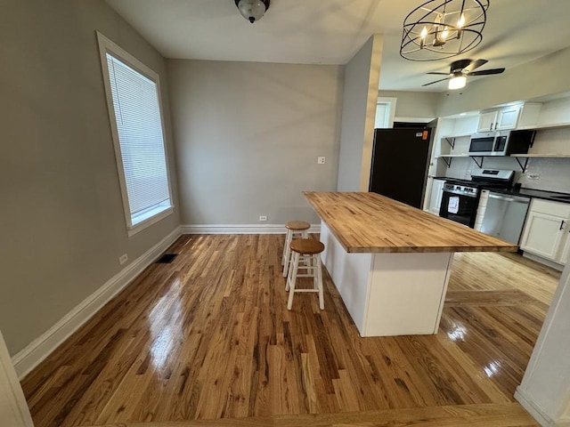 6116 S Ellis Ave Unit 1, Chicago, IL 60637 - kitchen featuring wooden counters, open shelves, appliances with stainless steel finishes, a breakfast bar area, and ceiling fan