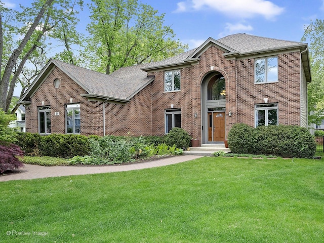 traditional home featuring roof with shingles, brick siding, and a front lawn