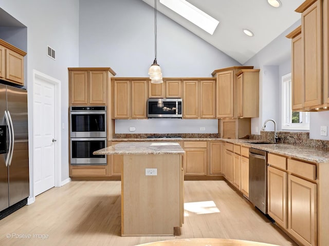 kitchen with appliances with stainless steel finishes, light brown cabinets, a sink, high vaulted ceiling, and a kitchen island