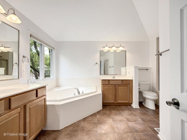 bathroom featuring a garden tub, toilet, two vanities, and vaulted ceiling
