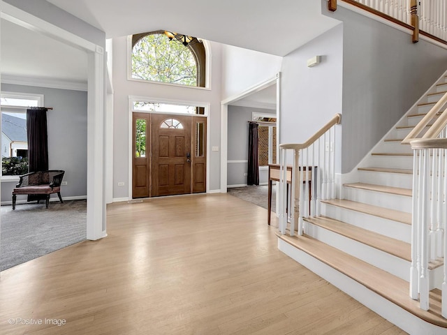 foyer entrance featuring healthy amount of natural light, wood finished floors, stairway, and a high ceiling