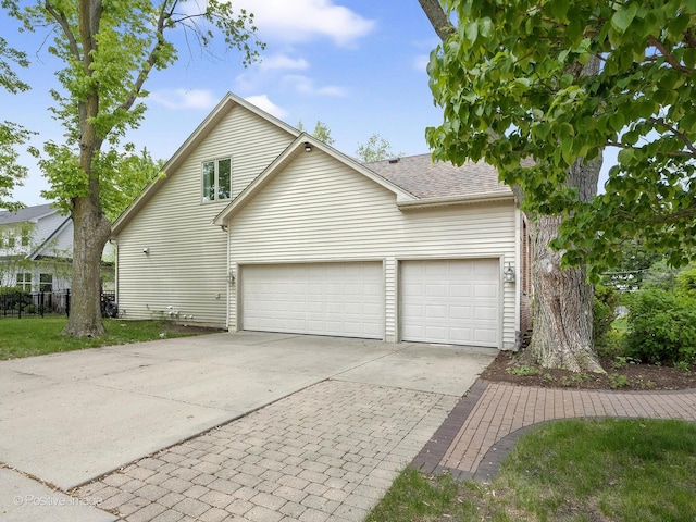 view of property exterior featuring driveway, a garage, and a shingled roof