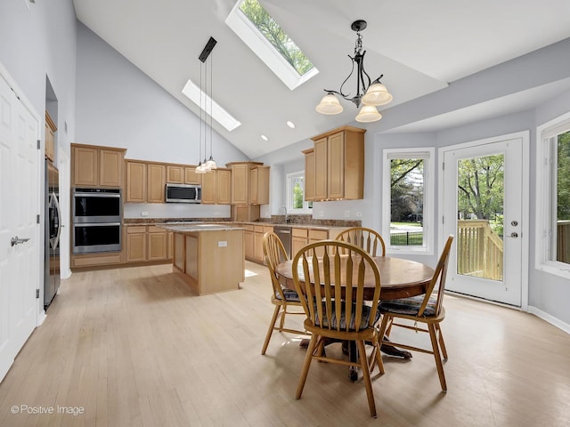 dining space with a skylight, light wood-style floors, and high vaulted ceiling
