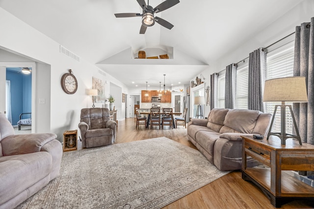 living area featuring ceiling fan, light wood-style flooring, and lofted ceiling