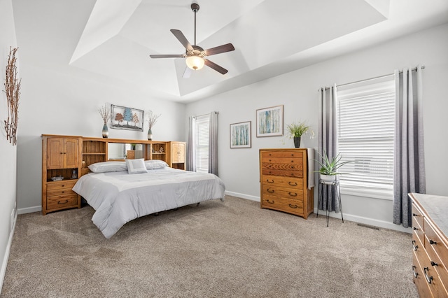 carpeted bedroom featuring a tray ceiling, baseboards, and ceiling fan