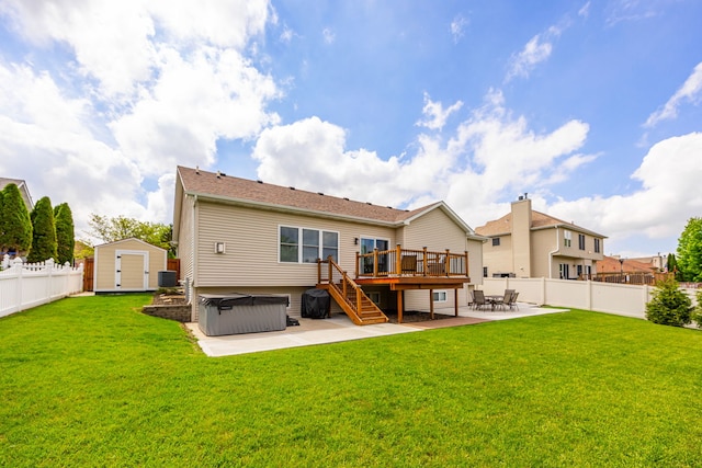 rear view of property featuring a hot tub, a patio area, a deck, a shed, and an outbuilding