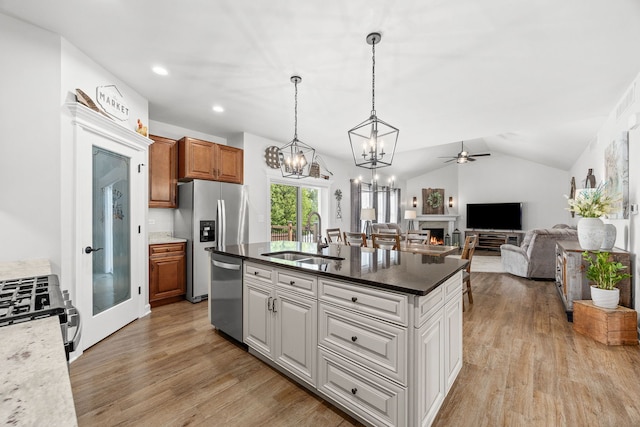 kitchen featuring stainless steel appliances, a sink, ceiling fan, light wood-style floors, and a kitchen island with sink