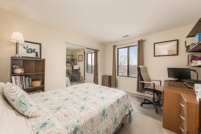 bedroom featuring light colored carpet, an office area, a closet, and baseboards