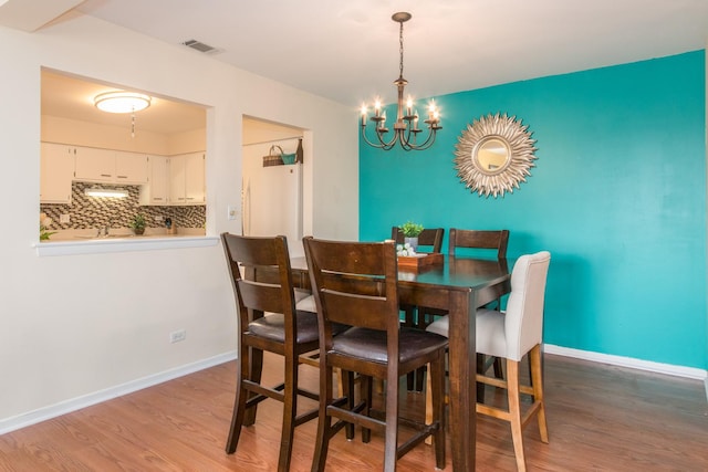 dining room featuring a chandelier, wood finished floors, and baseboards