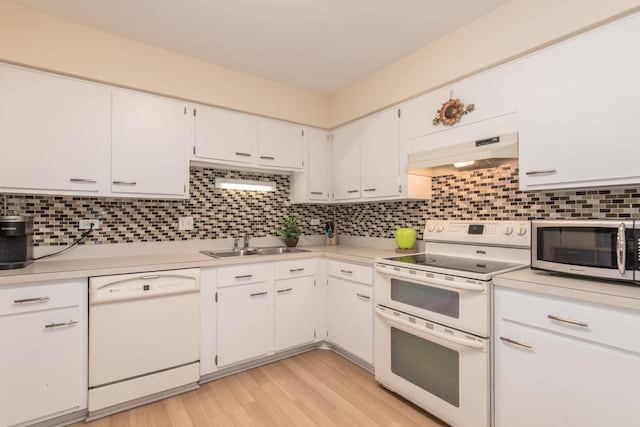 kitchen with white appliances, under cabinet range hood, a sink, and light countertops
