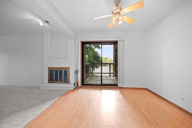 1502 Woodbridge Rd Unit 1D, Joliet, IL 60436 - unfurnished living room featuring brick wall, a brick fireplace, wood finished floors, a ceiling fan, and baseboards