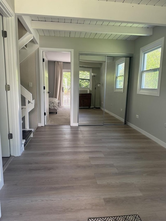 interior space featuring beamed ceiling, baseboards, and wood finished floors