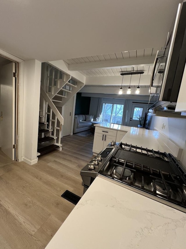 kitchen with light wood-style floors, white cabinets, light countertops, beam ceiling, and pendant lighting