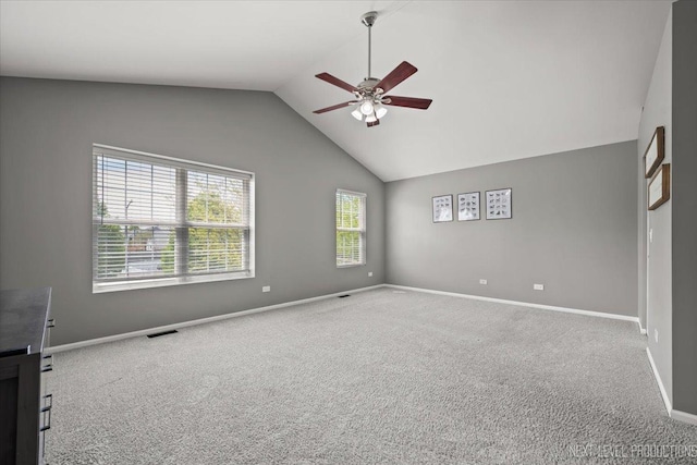 empty room with ceiling fan, carpet floors, lofted ceiling, and baseboards