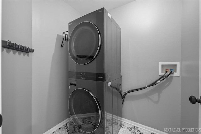 washroom with estacked washer and dryer and baseboards