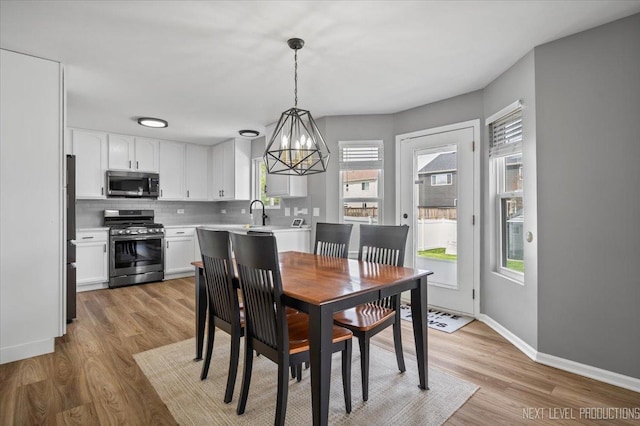 dining area featuring a chandelier, baseboards, and light wood-style flooring