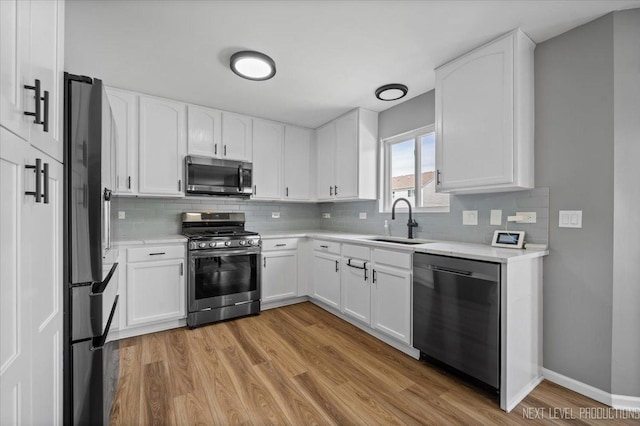 kitchen with stainless steel appliances, a sink, light wood-style flooring, light countertops, and backsplash