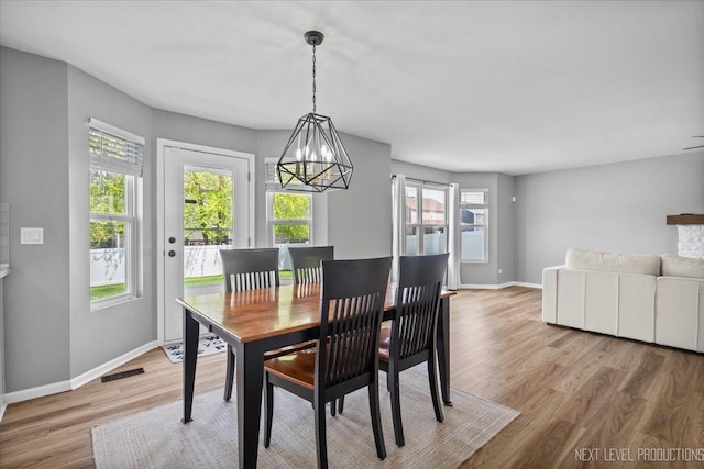 dining area featuring wood finished floors, healthy amount of natural light, a chandelier, and baseboards