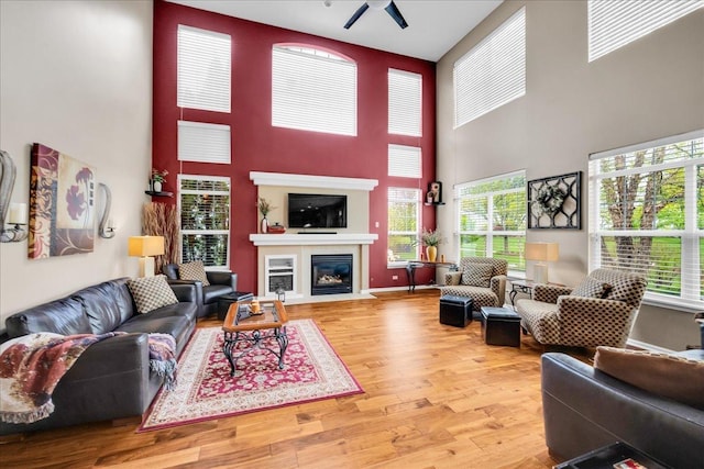 10905 Manhattan Dr, Huntley, IL 60142 - living area featuring a towering ceiling, a ceiling fan, wood finished floors, a fireplace with flush hearth, and plenty of natural light