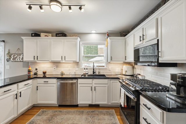 423 W Taylor St W, Dekalb, IL 60115 - kitchen featuring appliances with stainless steel finishes, white cabinets, wood finished floors, and dark countertops