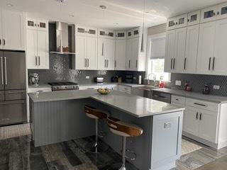 313 Roger Rd, Darien, IL 60561 - kitchen with wall chimney range hood, freestanding refrigerator, a kitchen island, decorative backsplash, and a breakfast bar