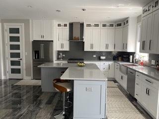 313 Roger Rd, Darien, IL 60561 - kitchen with black fridge, a kitchen island, wall chimney range hood, dishwasher, and a kitchen bar