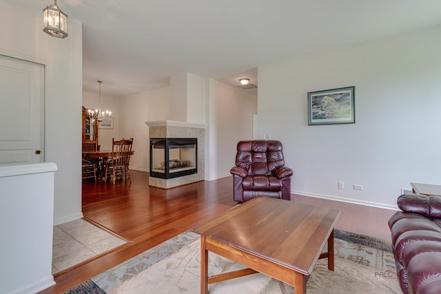 604 S Essington Dr, Round Lake, IL 60073 - living room featuring wood finished floors, a chandelier, a tiled fireplace, and baseboards