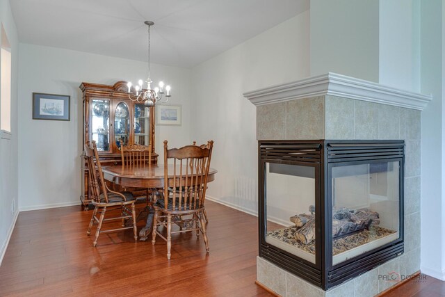 604 S Essington Dr, Round Lake, IL 60073 - dining room featuring a chandelier, wood finished floors, a tiled fireplace, and baseboards