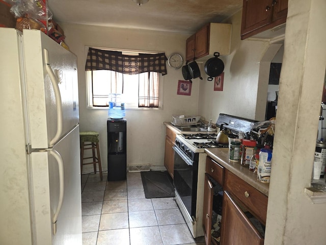 5703 S Aberdeen St, Chicago, IL 60621 - kitchen featuring freestanding refrigerator, range with gas stovetop, light tile patterned floors, brown cabinets, and light countertops