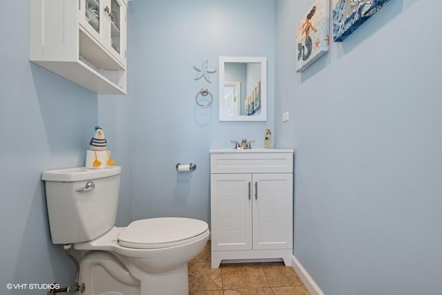 half bath with toilet, vanity, tile patterned flooring, and baseboards