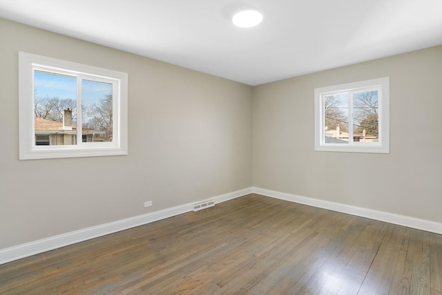 empty room featuring baseboards and dark wood-type flooring