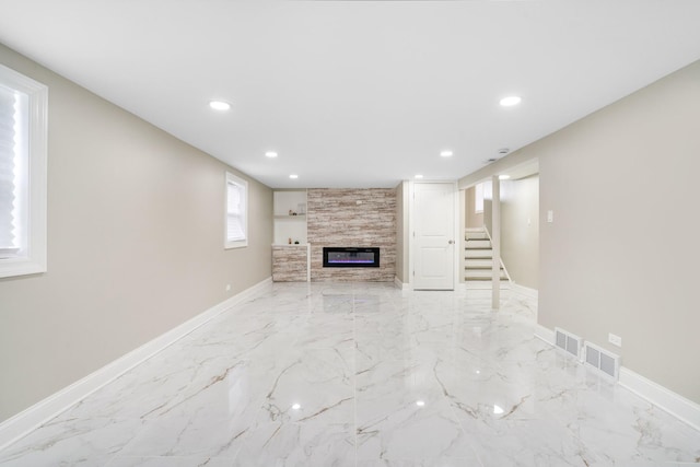 unfurnished living room with a fireplace, recessed lighting, light marble finish floors, baseboards, and stairs