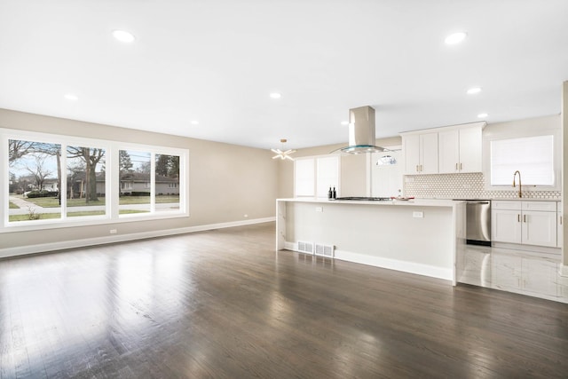 unfurnished living room with healthy amount of natural light, wood finished floors, baseboards, a sink, and recessed lighting