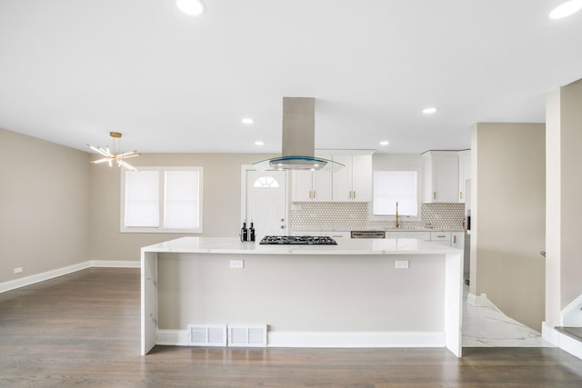kitchen featuring island exhaust hood, gas stovetop, a spacious island, light countertops, and white cabinets