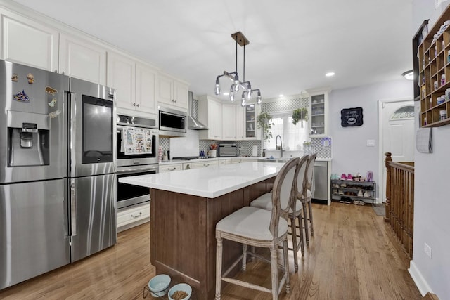 884 Arnold Ct, Des Plaines, IL 60016 - kitchen featuring appliances with stainless steel finishes, a sink, glass insert cabinets, tasteful backsplash, and light wood finished floors
