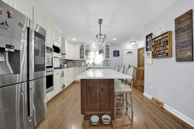 884 Arnold Ct, Des Plaines, IL 60016 - kitchen featuring appliances with stainless steel finishes, white cabinets, light wood-style flooring, baseboards, and recessed lighting