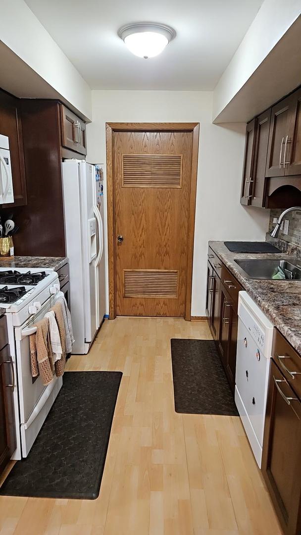 9230 Hartwood Ct Unit 1404, Orland Park, IL 60462 - kitchen with white appliances, a sink, dark brown cabinetry, and light wood-style flooring