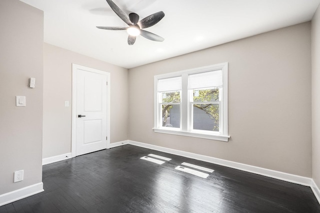 empty room with baseboards, a ceiling fan, and dark wood-style floors