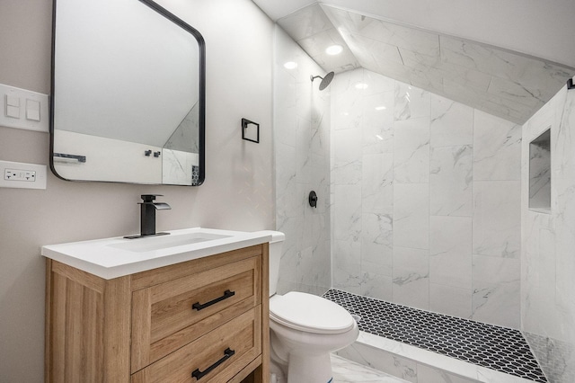 bathroom with marble finish floors, tiled shower, vanity, and toilet