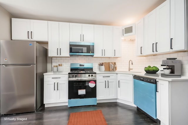 kitchen featuring appliances with stainless steel finishes, light countertops, white cabinets, tasteful backsplash, and a sink