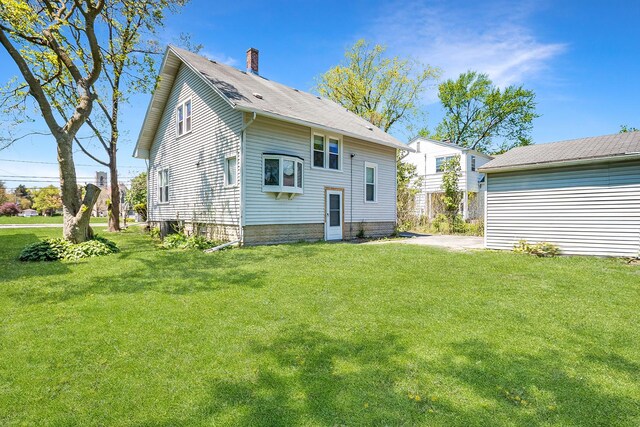 rear view of property featuring a chimney and a yard