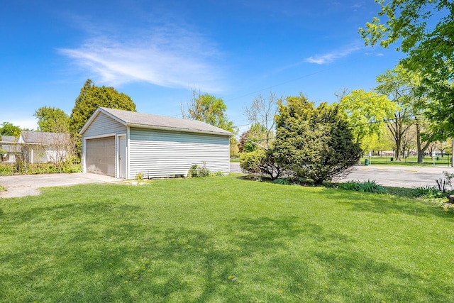 view of green lawn featuring a garage and an outbuilding